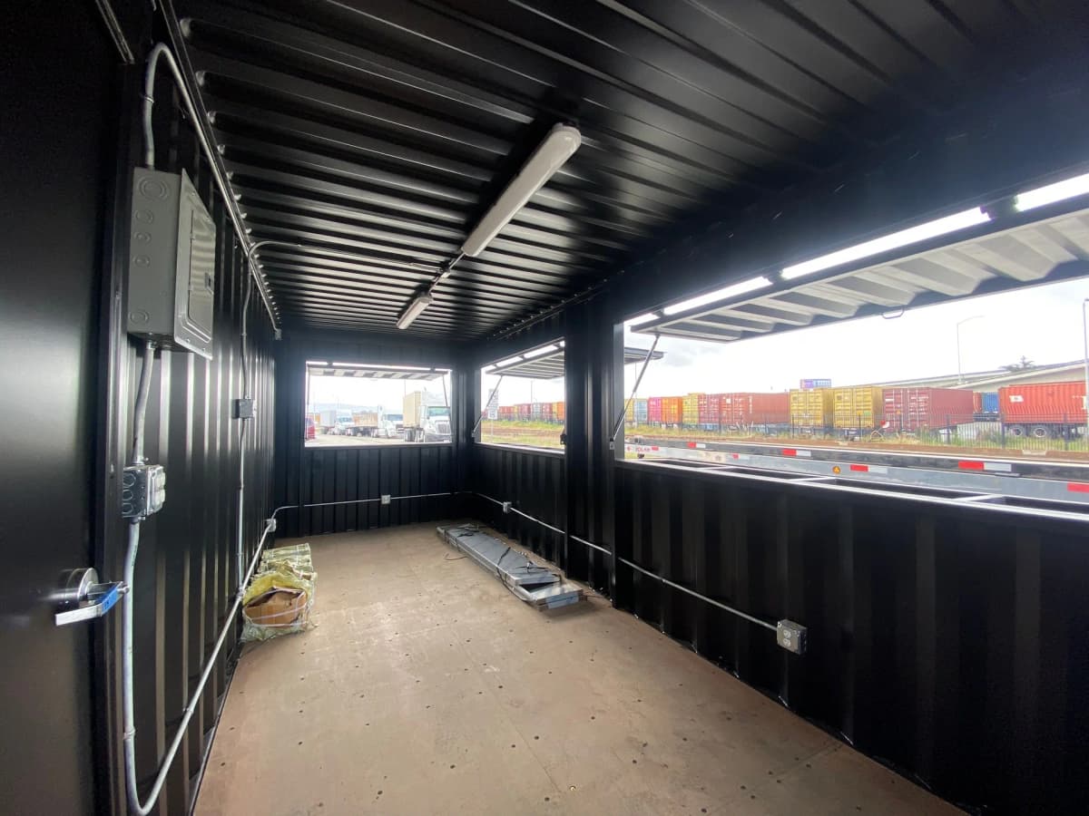 Exterior of an industrial shipping container bar with awnings and service counters