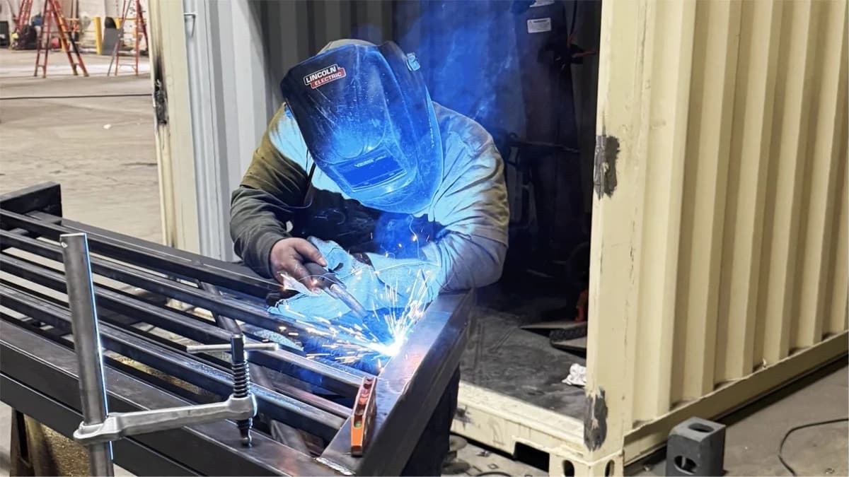 Welder working on metal frame of shipping container