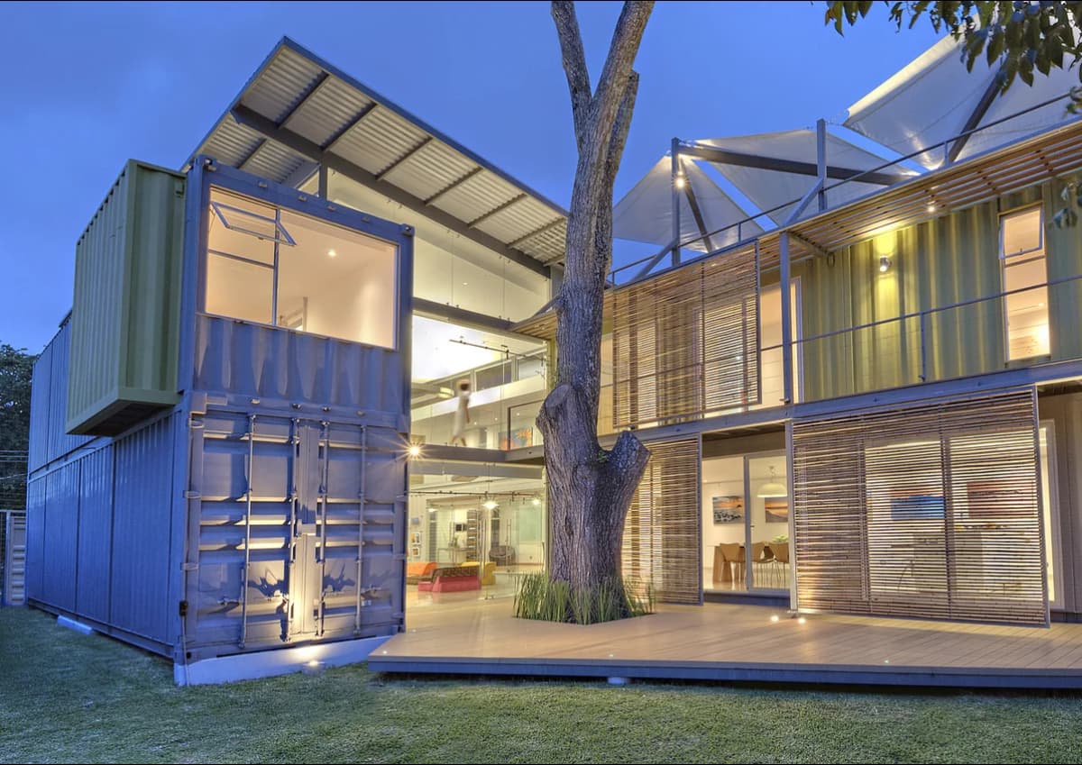 A modern shipping container home with exterior stairs and large windows.
