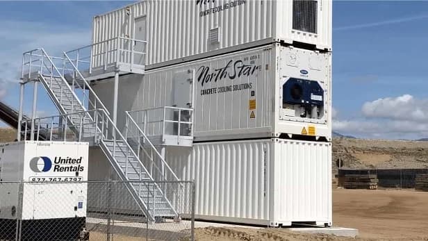 Multi-level shipping container structure with stairs and balconies, showing a stacked container housing unit.