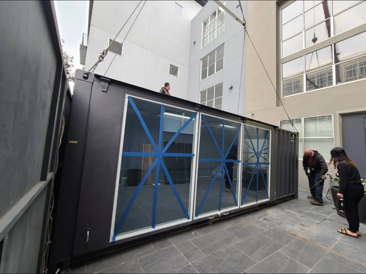 The Conexwest team working on a shipping container with glass walls.