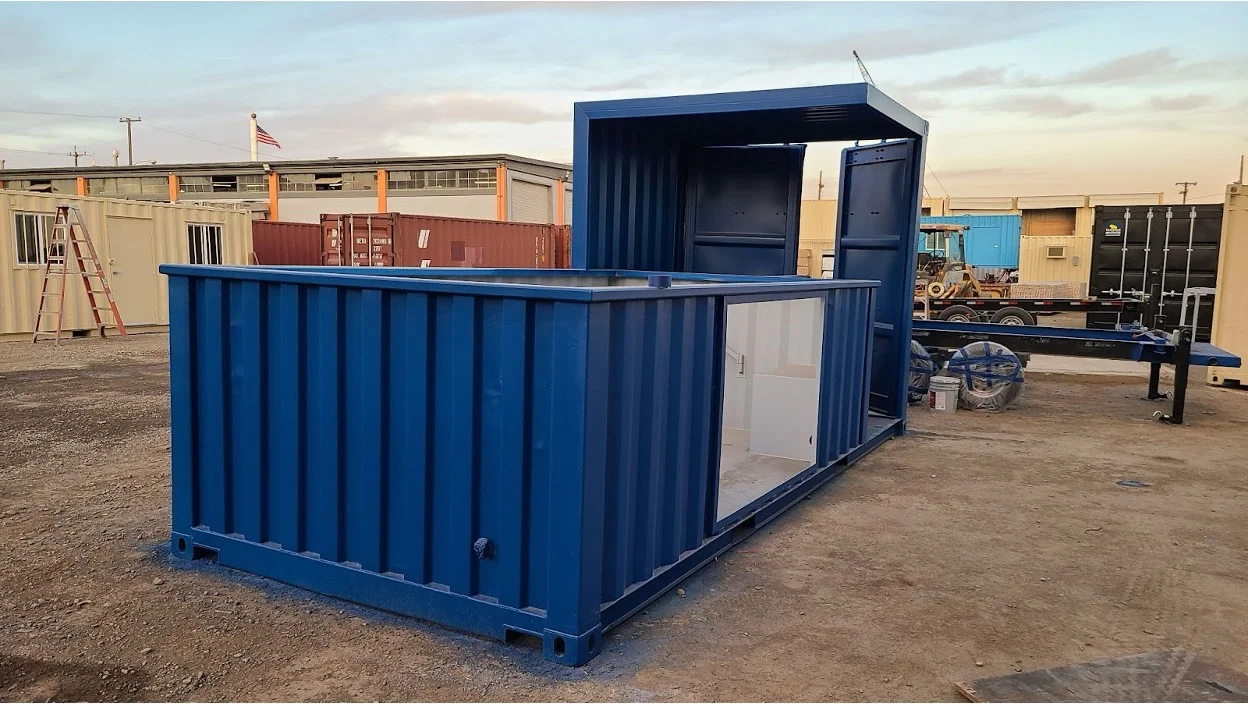 A blue shipping container that is opened up with the upper half removed in a lot.