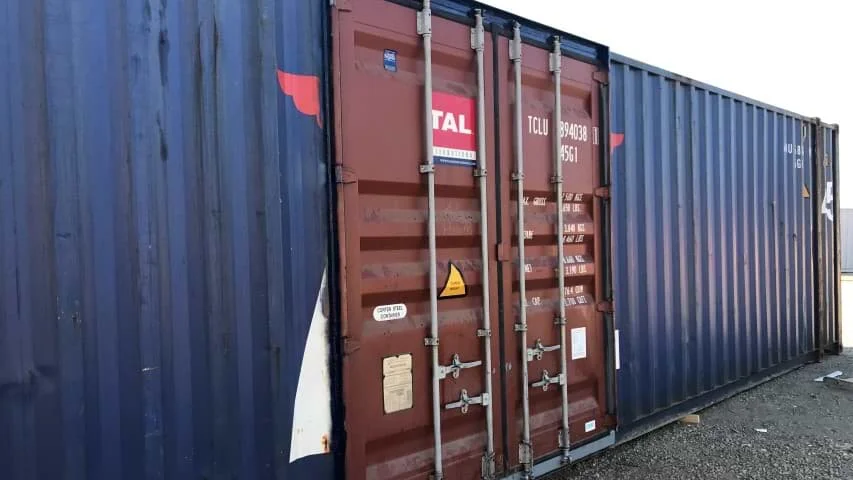 A blue shipping container with a brown door installed on its long side